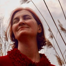 Photo of Emma Donogue in smiling with eyes closed in tall grass